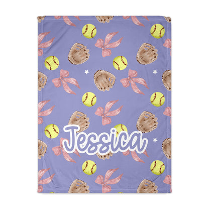 Personalized blanket with softball, glove, and bow pattern on a purple background